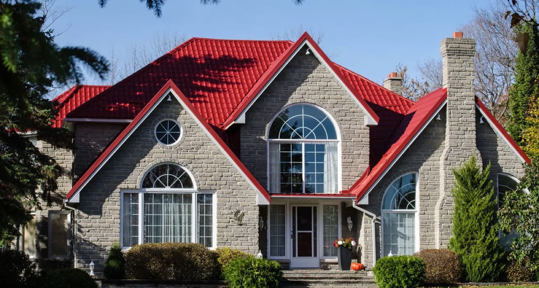 Two-storey stone home with a red Rudan steel roof