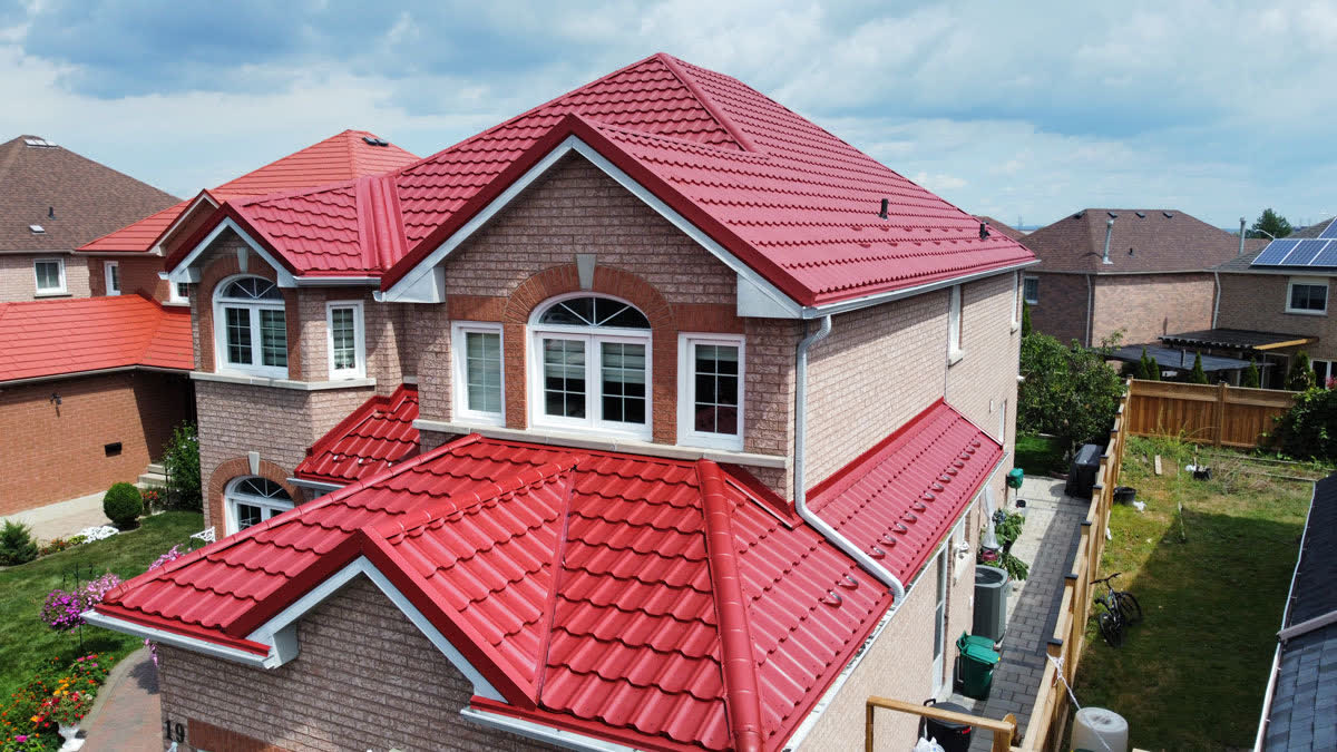Brick home with a bright red steel tile roof